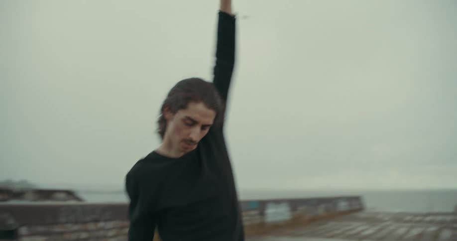 A ballet dancer dances on a pier outdoors