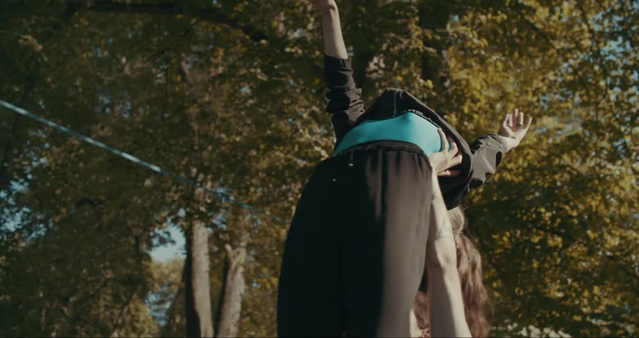 A man and a woman are outside dancing and he lifts her into the air as she strikes a pose