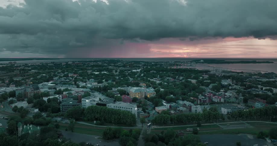 Dark clouds loom over a city on the coast in the evening