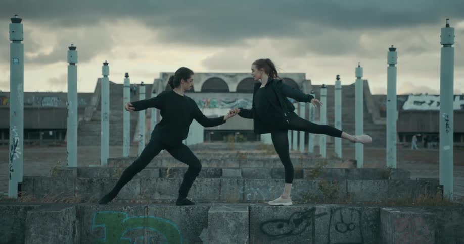 Young couple dancing ballet over concrete steps outdoors at sunset