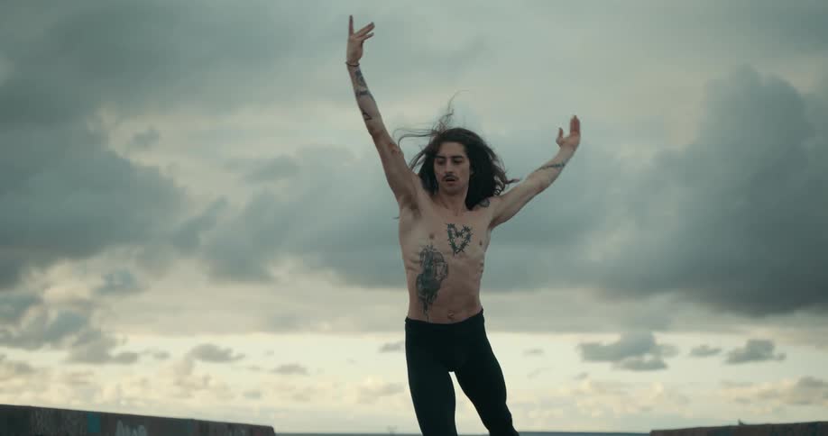 A ballet dancer twirls and leaps holding his pose showing strong arms and bare chest