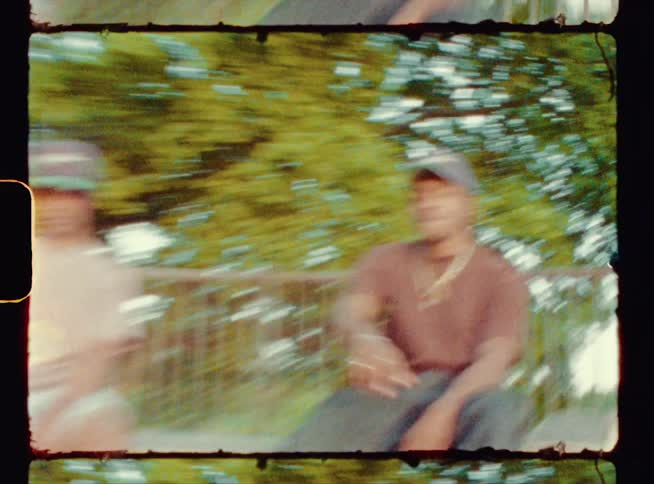 A group of skateboarders and cyclists laugh as they hang out at a skate park