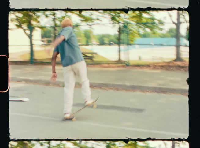 A woman balances riding on the back wheels of a skateboard as her friend looks on