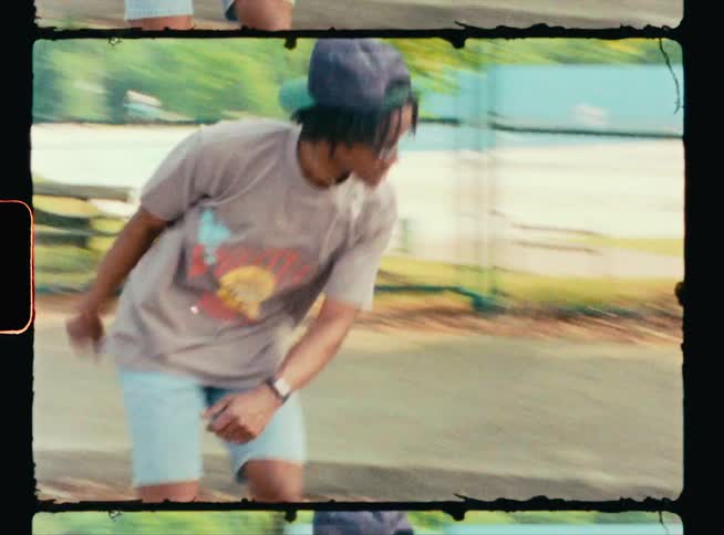 A young man flips his skateboard during a jump and high fives a woman sitting on the curb watching