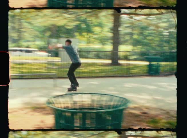 A teenage boy skates across a park bench