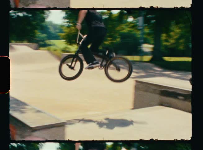 A bicyclist jumps and spins in the air during a trick at a skate park
