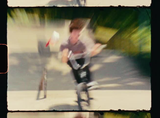 A young man rides and jumps his bike up a railing at a skate park losing his cap on the landing