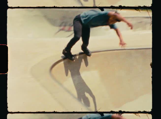 A young man skateboards up a slope and along a narrow edge and back down