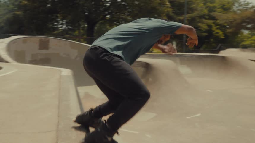 A skateboarder jumps onto and rides along the edge of a skate park