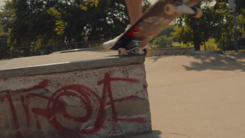 A teenage boy skateboards up and across a ledge and off of it