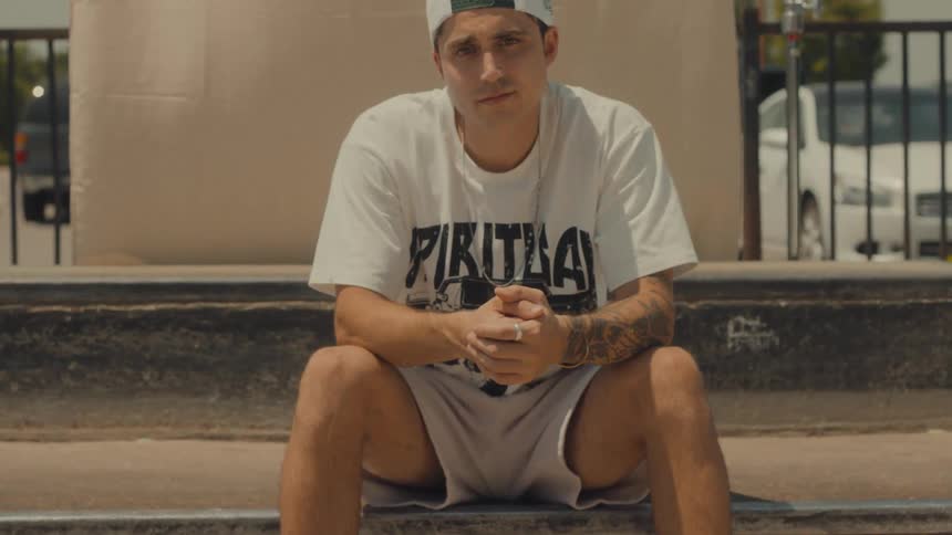 A teenage boy sits outside and poses for a photo