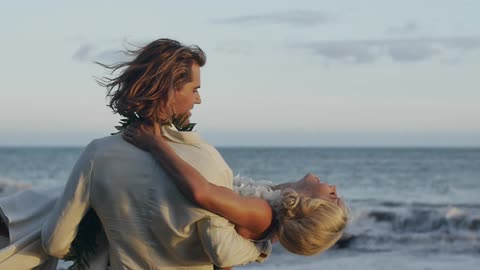 A man is carrying a woman on the beach