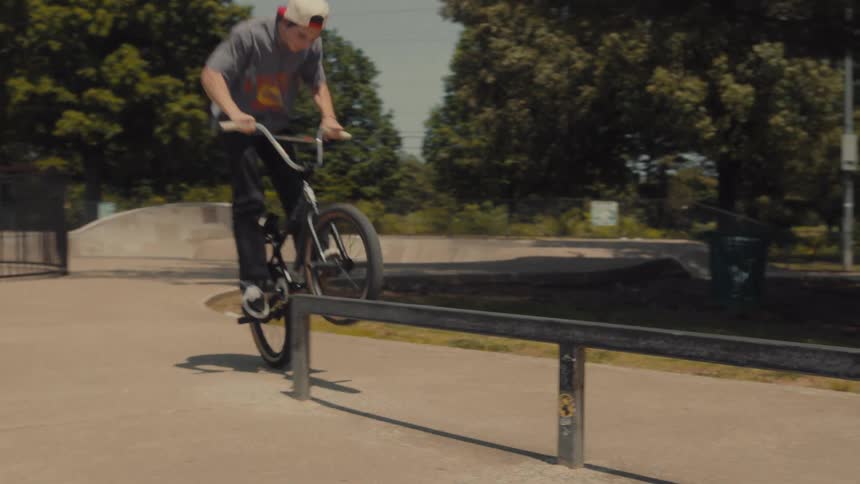 A bicyclist jumps onto a metal bar in a skate park