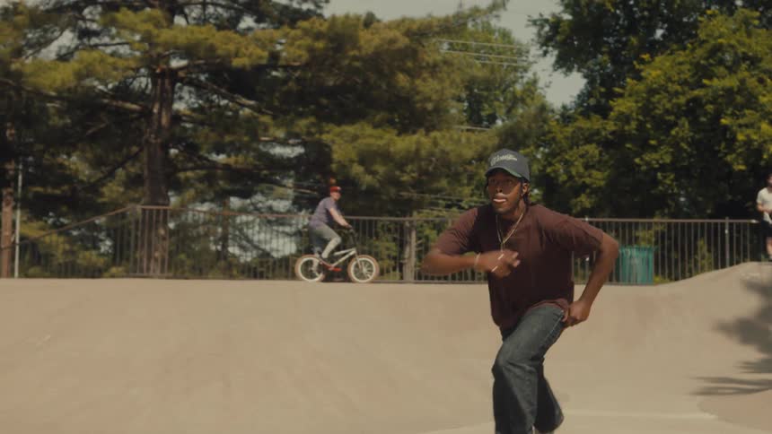 A young man skates between two concrete slopes at a public skate park