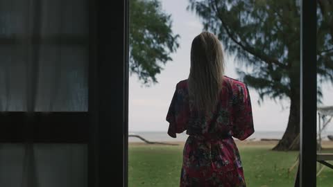 Woman in robe standing and looking out a window