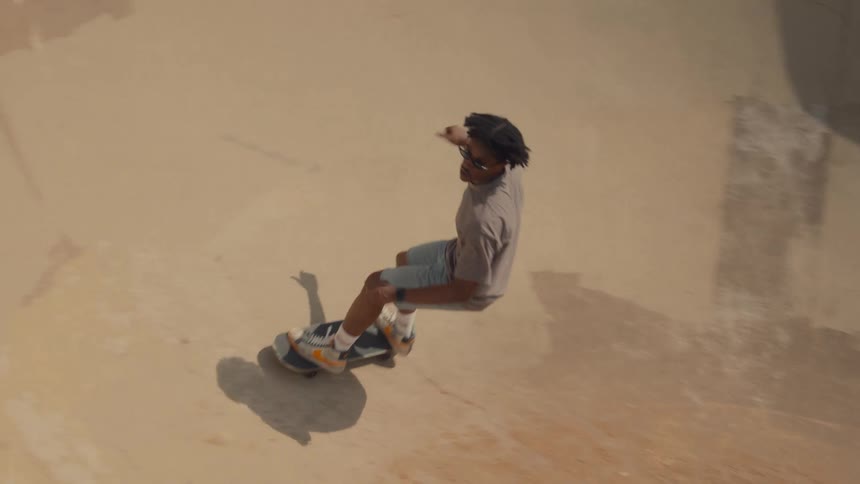 A teenage boy is riding his skateboard in a concrete bowl at a skate park