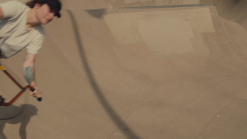 A teenage girl bikes up and down ramps at a park