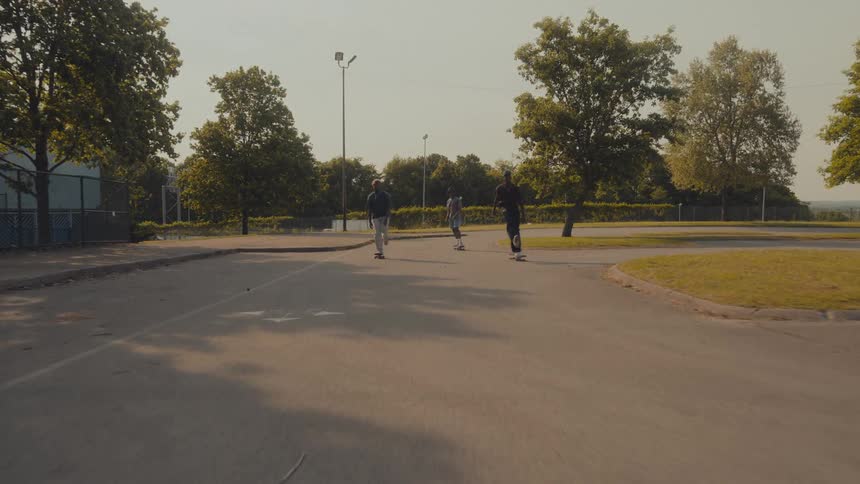 A group of people ride their skateboards side by side through a parking lot