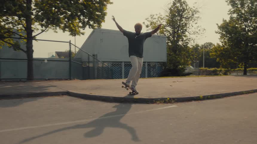 Two men ride their skateboards past a park