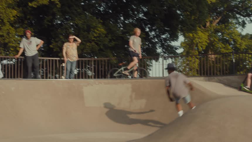 A teenage boy is riding his skateboard at a skateboard park and people are watching him