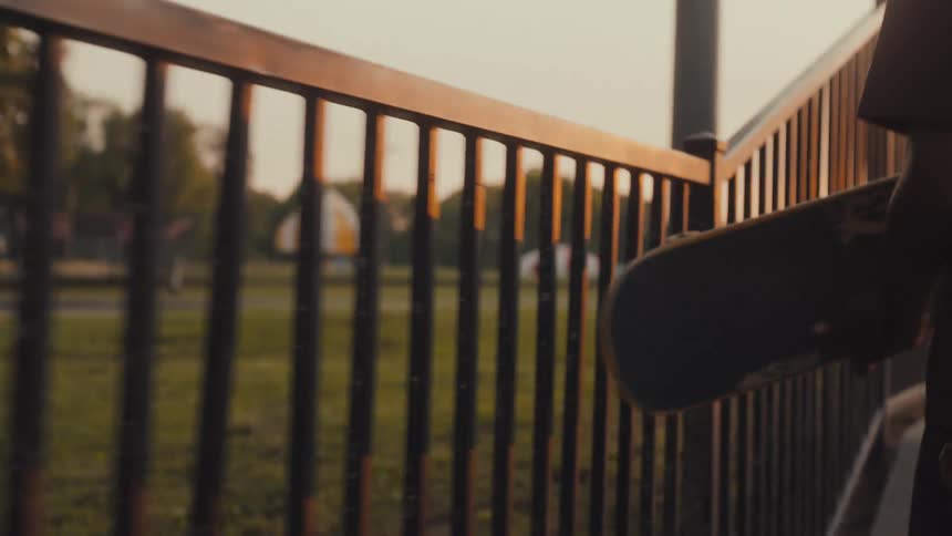 A young man runs his skateboard along the railing before dropping it and riding in the skate park