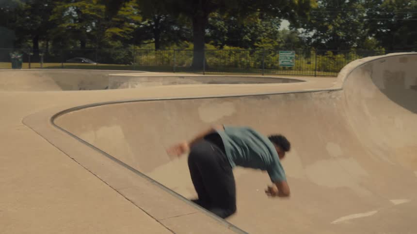 A skateboarder rides along the rim at a skate park