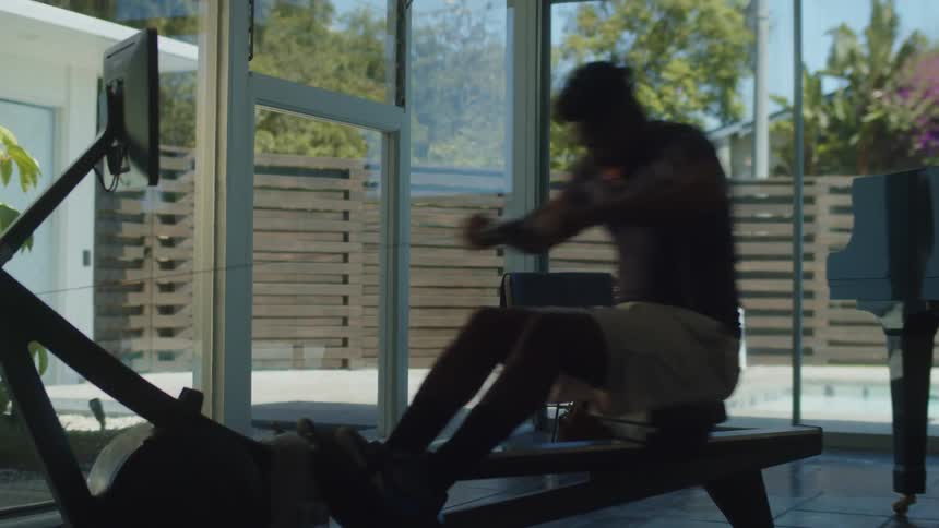 A man works out on a rowing machine at home