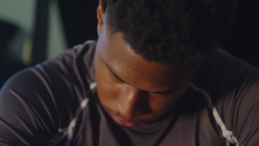 A mans face is covered with sweat as he works out with a rowing machine