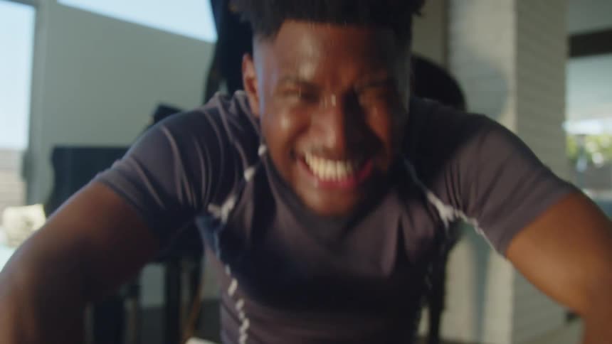 A man at home breathes heavy as he works out on a rowing machine