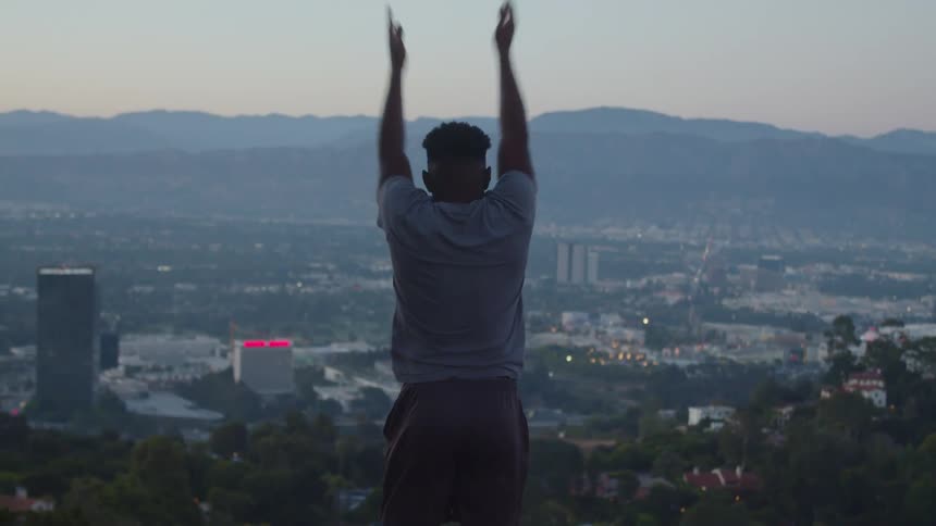 A young black man is working out overlooking downtown area