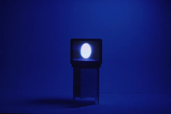 An egg shaped sphere plays on a television in a dark room