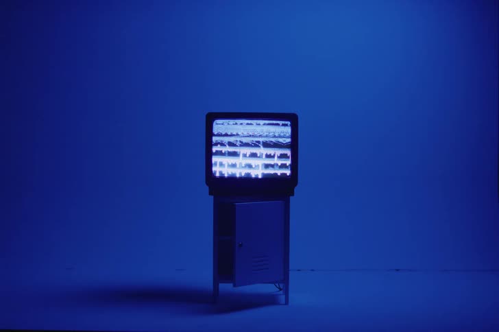 Blue colored lighting casts shadow of television sitting on stand