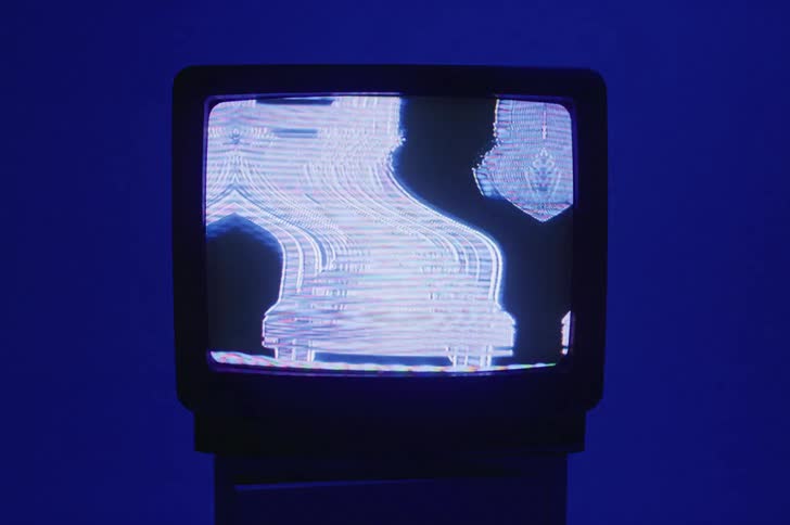 A vintage television with a fuzzy screen sits on a stand