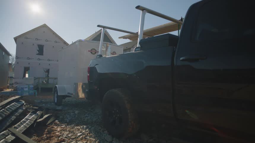 A pickup truck is parked in front of a home under construction