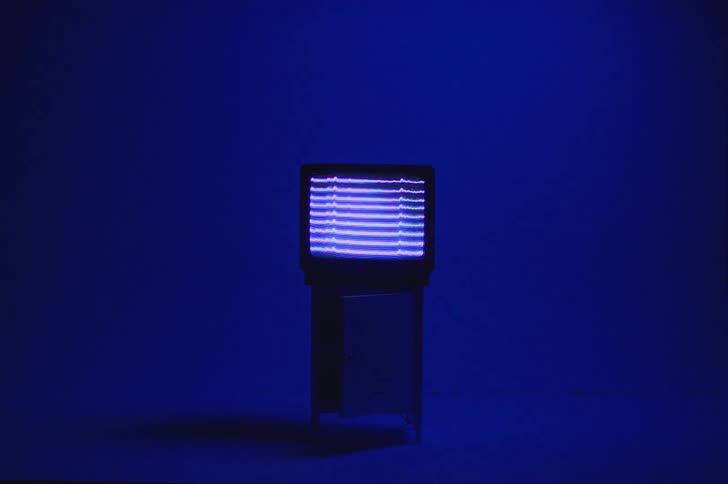 Television sitting on stand displays digital signal in room lit by blue lighting