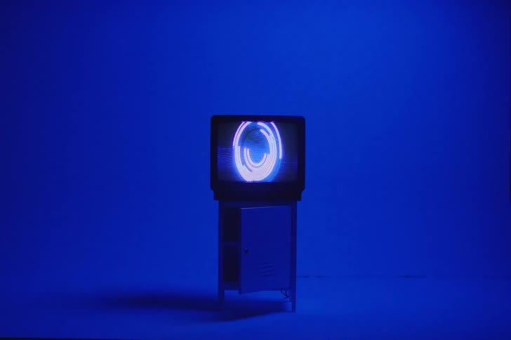 A television is an a blue room and geometrical images and lines flash across the screen