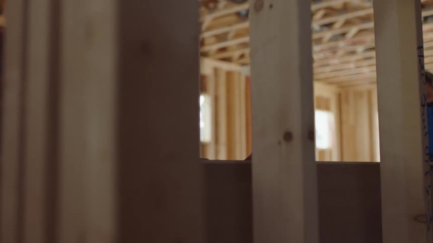 Two construction employees are building a house