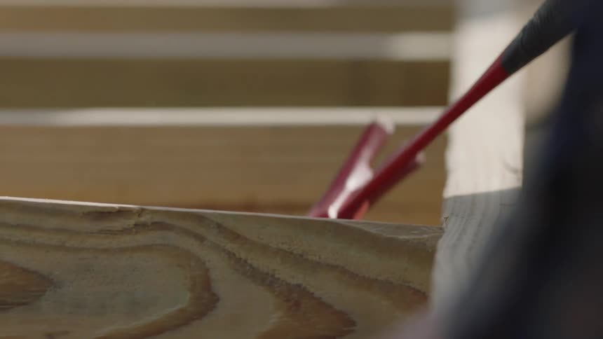 Construction worker hammers post into place in wooden frame