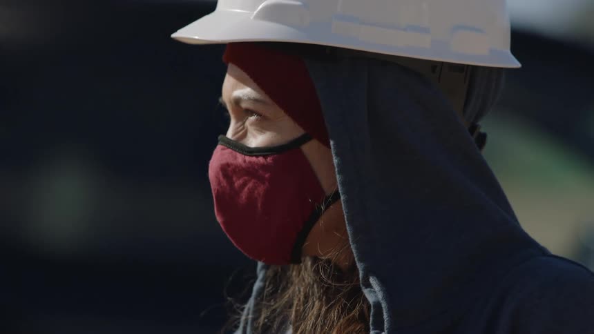 Afemale construction employee is standing outdoors