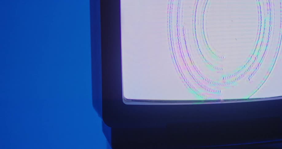 Purple and green circles move on a white screen on a television in a room with blue walls