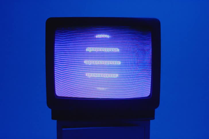 Lines and designs move on a television screen and the deep blue wall gets lighter and darker