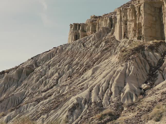 Rock slope reaches base of cliff under a cloudy sky
