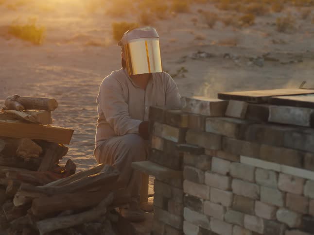 There is a man sitting down by the desert in the day time