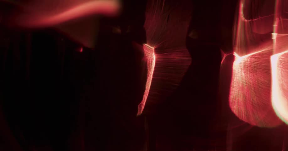Orange luminous objects rotate as they glow and move across the darkness emitting a ghostly aura