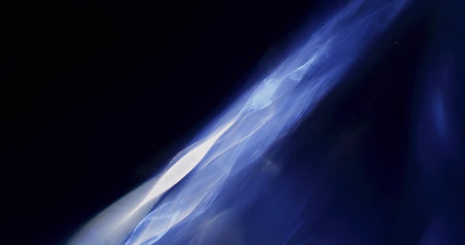 White glowing wisps with a blue aura spread out as they move across the darkness