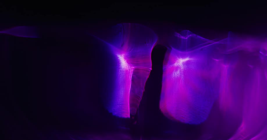 Colorful glowing and shimmering light reflecting on smoke against a black background