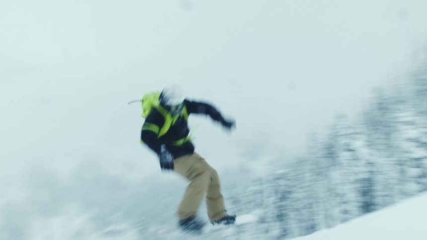 A snowboarder jumps and spins on a mountain slope while skiers watch