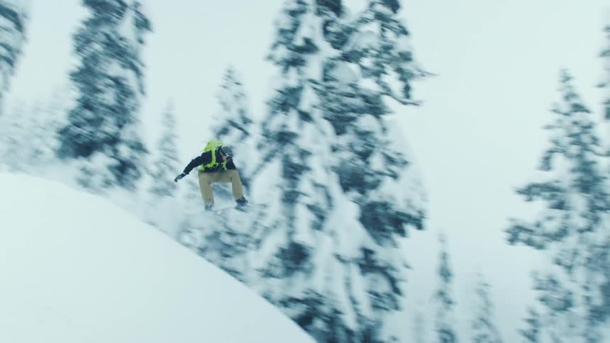 A snowboarder lands a jump off a snow ramp on a mountain slope