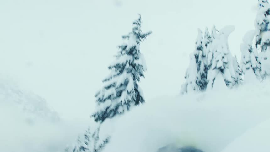 A snowboarder jumping and landing in a pile of powder snow in winter