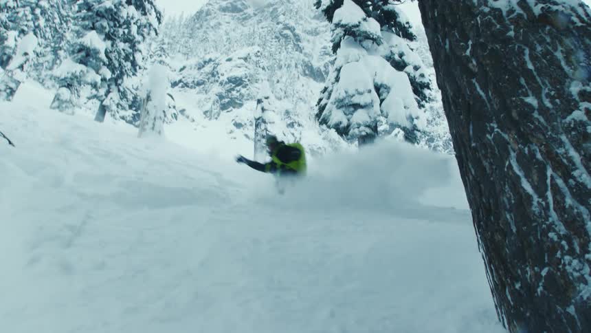 A person is snowboarding in a forest during winter
